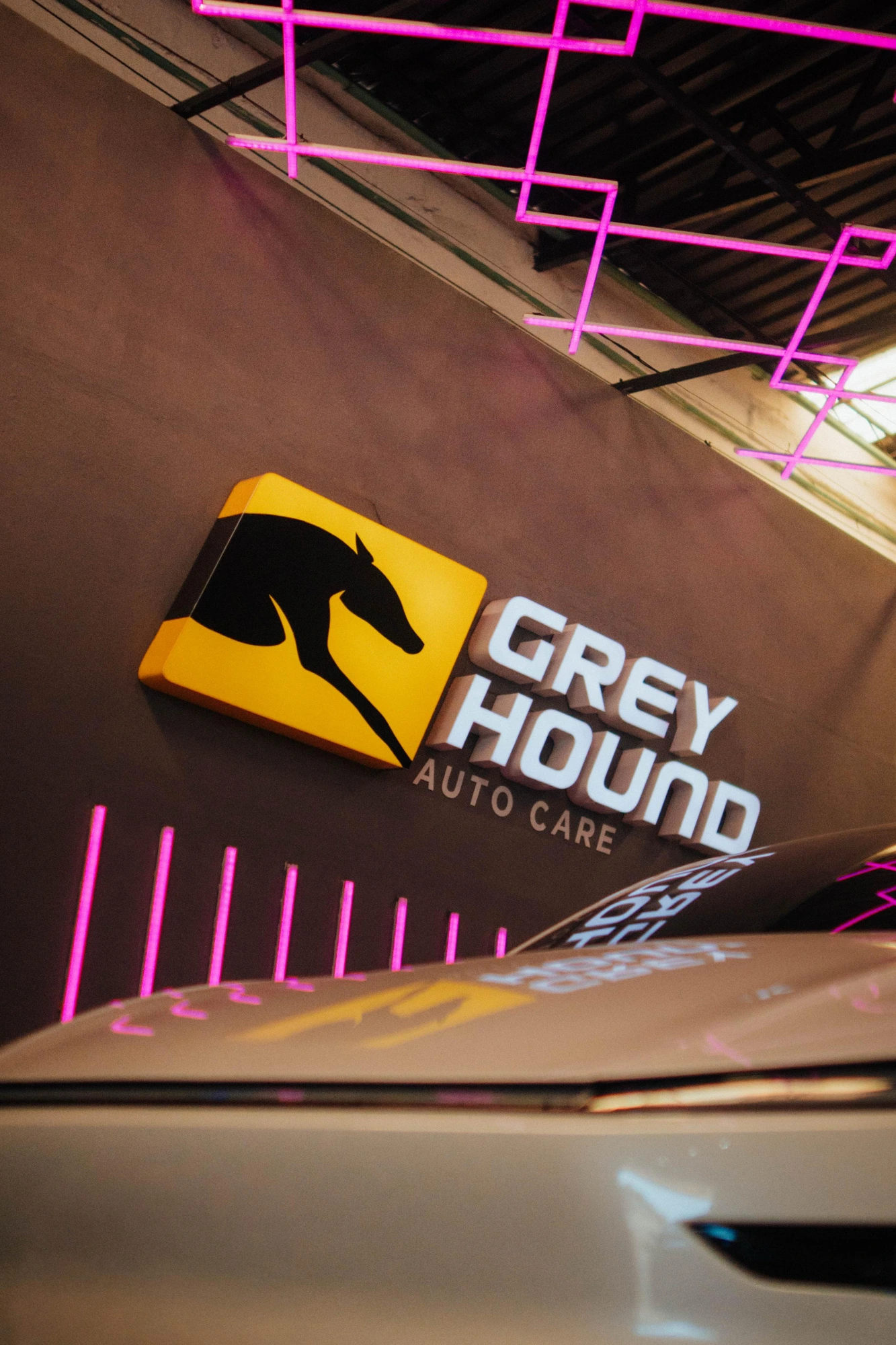 Logotipo de Grey Hound Auto Care iluminado en la pared del taller